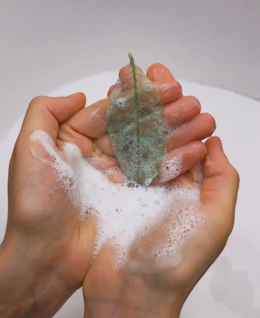 Soapy hands holding a leaf.